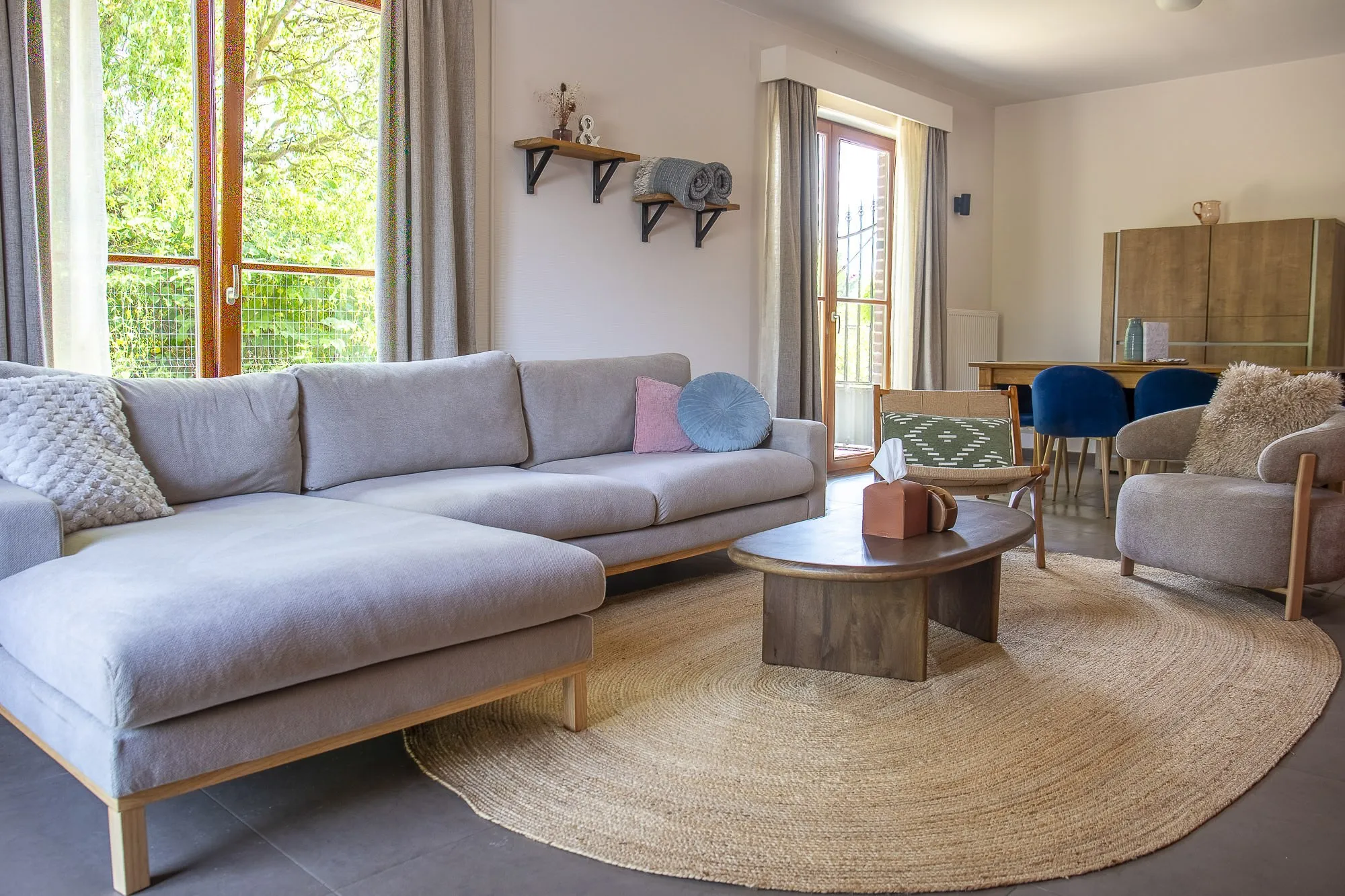 Wohnzimmer mit grauem Sofa, Essbereich und Blick in den Garten