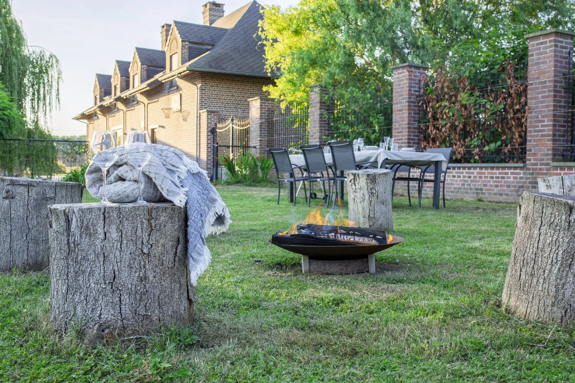 Garten des Ferienhauses mit Feuerschale, gedecktem Tisch und Backsteinfassade